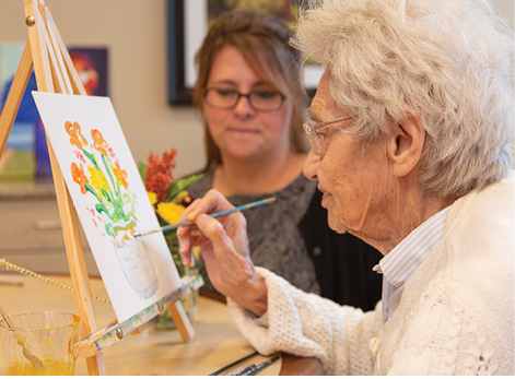An elderly woman is painting a picture while a woman watches. AI generated content